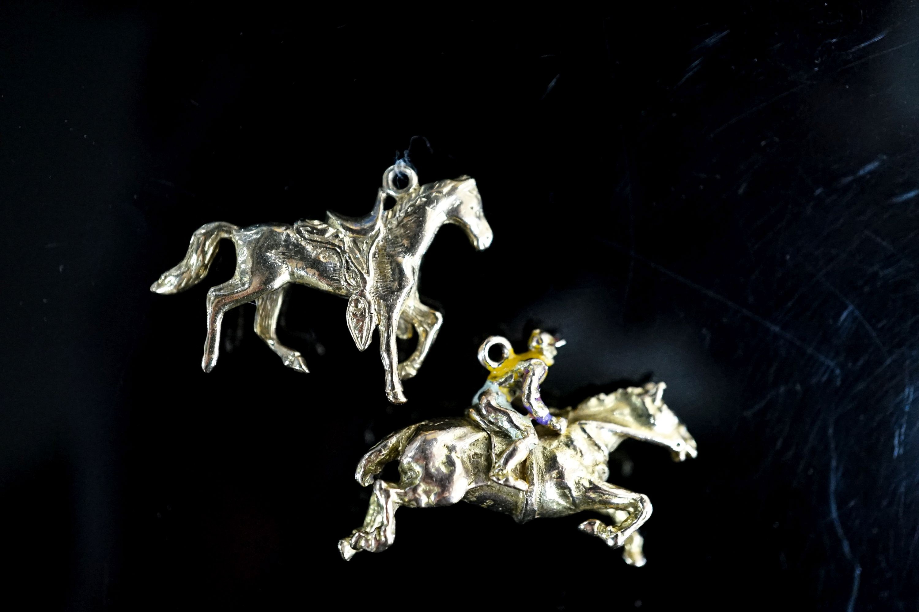 Two 9ct gold horse pendant charms including enamelled horse and jockey(a.f.), 33mm, gross 14.7 grams.